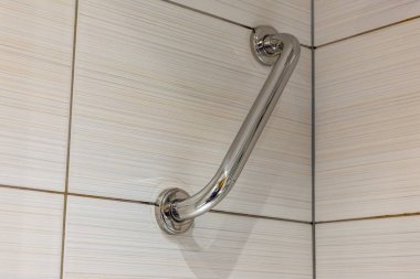 Krom banyo sapı duş kabininin duvarına monte edilmiş. Banyo seramik kiremitlerle dolu.