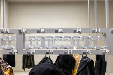 Ceketler ve ceketler vestiyerde asılı. Fotoğraf bir kamu hizmetleri binasında yapay ışık altında çekildi