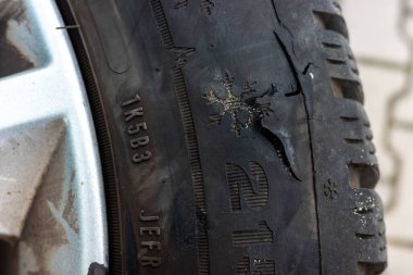 Keskin yol engellerine takıldıktan sonra araba lastiği parçalandı. Lastiğin kenarında büyük bir delik var.