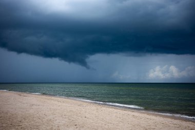 Şiddetli, karanlık fırtına bulutları deniz ufkunda toplanıyor. Yeşil, sakin sular yaklaşan hava değişiminden önce.