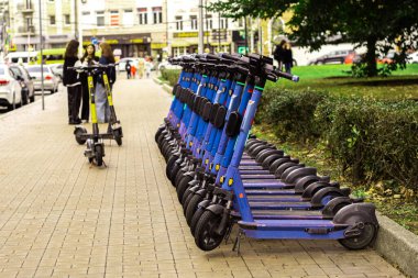 Şehirdeki park yerinde mavi elektrikli scooterlar. Kiralık scooter. Kentte ekolojik ve kentsel ulaşım.