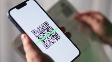 Akıllı telefonu QR kodunu taramak için kullanan bir kadın. Plastik kart konsepti olmayan dijital ödeme. QR kod ödemesi