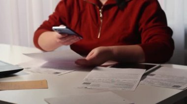 Evdeki akıllı telefondan faturaları ödeyen bir kadın. Fatura ödeme konsepti. İnternet bankacılığı ve qr kodu kullanılarak dijital ödeme