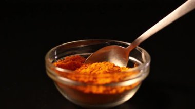 Koyu arkaplanda bir kaşık zerdeçal tozu izole edilmiş. Canlı turuncu baharat rengi. Sağlıklı zerdeçal içeceği için barut bileşeni. Detoks kavramı