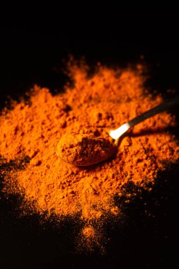 Koyu arkaplanda bir kaşık zerdeçal tozu izole edilmiş. Canlı turuncu baharat rengi. Sağlıklı zerdeçal içeceği için barut bileşeni. Detoks kavramı