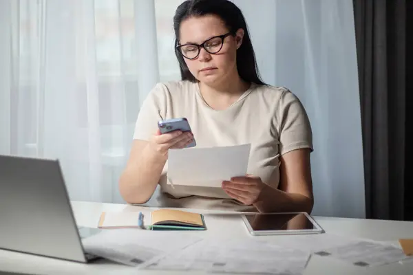 Evdeki akıllı telefondan faturaları ödeyen bir kadın. Fatura ödeme konsepti. İnternet bankacılığı ve qr kodu kullanılarak dijital ödeme