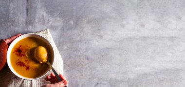 Kadın, biber baharatlı ve beyaz masada kremalı balkabağı çorbası tadıyor. Mutfak peçetesi. Fotokopi alanı olan düz bir yer. Krema çorbası. Lezzetli sağlıklı yiyecek kavramı.