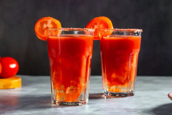 Bardakta iki Bloody Mary kokteyli, domates dilimi ve koyu arkaplanda tuz. Kırmızı kokteyl. Alternatif tat. Kirli içki.