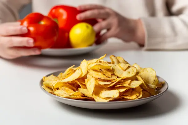 Kızarmış cips ve sebzeli tabak. Sağlıklı beslenmeyi fast food 'a tercih eden bir kadın. Kilo verme konsepti.