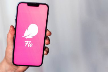 Kaliningrad, Rusya 14.01.25 FLO uygulama logosuna sahip akıllı telefonu ekranda tutan kadın. Kadın kontrolü, yumurtlama, hamilelik. Kadın sağlığı kavramı.