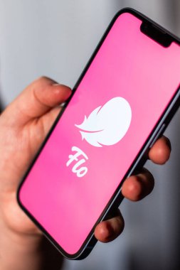 Kaliningrad, Rusya 14.01.25 FLO uygulama logosuna sahip akıllı telefonu ekranda tutan kadın. Kadın kontrolü, yumurtlama, hamilelik. Kadın sağlığı kavramı.