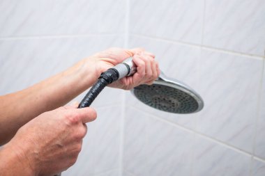 Kadın banyoda kırık duş hortumunu değiştiriyor. Kadın tesisatçı elleri hortumu tamir ediyor. Tesisat konsepti. Erkek ve kadın meslekleri konsepti.