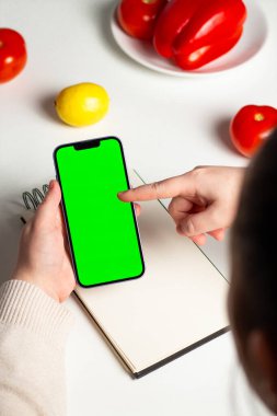 Bir kadının kilo vermek için diyet planı oluşturması. Not defterini ve yeşil ekranı hazırla. Sağlıklı yaşam tarzı uygulaması, web sitesi ve beslenme uzmanı için tasarım.