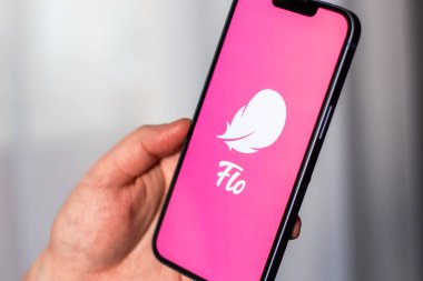 Kaliningrad, Rusya 14.01.25 FLO uygulama logosuna sahip akıllı telefonu ekranda tutan kadın. Kadın kontrolü, yumurtlama, hamilelik. Kadın sağlığı kavramı.