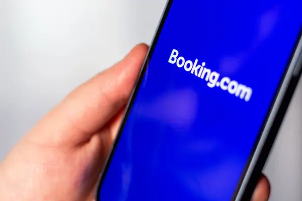 Kaliningrad, Rusya 14.01.25 BOOKINGCOM uygulaması olan akıllı telefonu ekranda tutan kadın. Daire ve otel araması. Seyahat planlama kavramı.