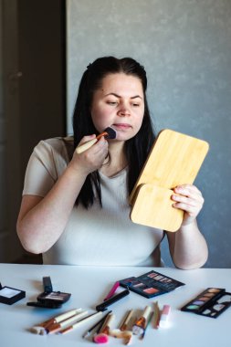 Millennial Kafkas kadınının makyaj tozu sürerken aynaya baktığı dikey görüntüsü. Hazırlanıyor. Güzellik konsepti.