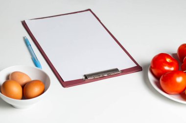 Beslenme planı ve diyet menüsünün boş taklidi. Sebze ve yumurtaların olduğu masada fotokopi alanı olan kağıt. Sağlıklı beslenme planı hazırlanıyor.