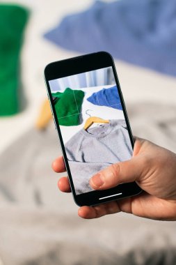 Kullanılmış süveterin fotoğrafını çekiyorum. İkinci el dükkanında satmak için kıyafet hazırlıyorum. İkinci el ve yeniden satış konsepti. Kıyafet bağışı.