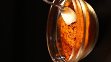 Koyu arkaplanda bir kaşık zerdeçal tozu izole edilmiş. Canlı turuncu baharat rengi. Sağlıklı zerdeçal içeceği için barut bileşeni. Detoks kavramı