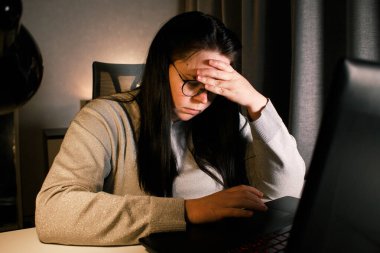 Baş ağrısı yüzünden bilgisayarda çalışan yorgun bir kadın kafasına dokunuyor. Migreni olan bir ofis çalışanı. İş yerinde acı çeken çok çalışan stresli bir çalışan.