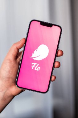 Kaliningrad, Rusya 14.01.25 FLO uygulama logosuna sahip akıllı telefonu ekranda tutan kadın. Kadın kontrolü, yumurtlama, hamilelik. Kadın sağlığı kavramı.