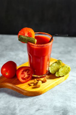 Koyu gri arka planda sallanan sebze kokteyli. Kırmızı domates kokteyli. Domates ve turşuyla servis edilir. Vegan menüsü.