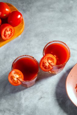 Bardakta domates dilimi ve koyu arkaplanda tuz ile servis edilen Bloody Mary kokteylinin en iyi görüntüsü. Kırmızı kokteyl. Alternatif tat. Kirli içki.
