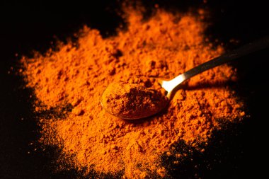 Koyu arkaplanda bir kaşık zerdeçal tozu izole edilmiş. Canlı turuncu baharat rengi. Sağlıklı zerdeçal içeceği için barut bileşeni. Detoks kavramı