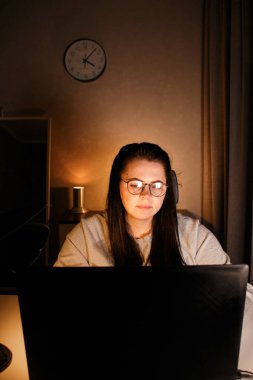 Ev ofisinde oturan uzaktan kumandalı bir kadın bilgisayar kullanarak çevrimiçi proje üzerinde çalışıyor. Gözlüklü kadın bilgisayar ekranından izliyor ve bilgi topluyor.