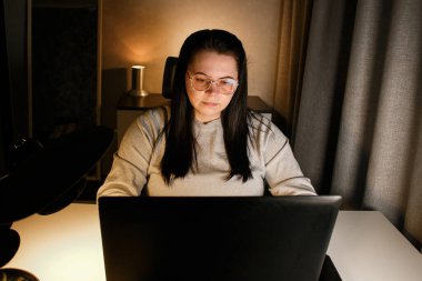 Odaklanmış iş kadını bilgisayarla sanal iş görüşmesi yapıyor. Evde oturan serbest çalışan, video konferansına katılıyor