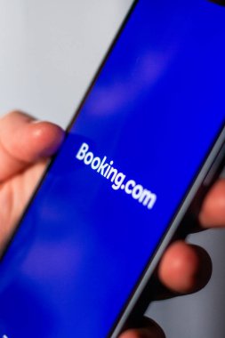 Kaliningrad, Rusya 14.01.25 BOOKINGCOM uygulaması olan akıllı telefonu ekranda tutan kadın. Daire ve otel araması. Seyahat planlama kavramı.