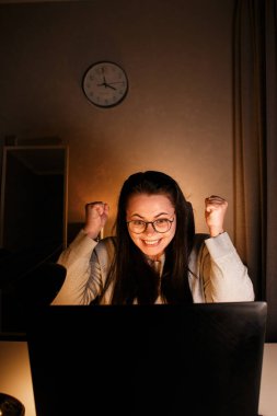 Neşeli milenyum kadını, bilgisayarını kullanarak arkadaşlarıyla görüntülü konuşma yapmaktan zevk alıyor. Hareketli ve gülümseyen. Uzakta yaşayan arkadaşlarla konuşmak. Uzun mesafeli dostluğa değer veren