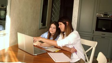 Aile dijital eğlence zamanı. Kafkas anne ve kızı dizüstü bilgisayar kullanarak online aktiviteler yapıyor, internette sörf yapıyor, iç mekanlarda video görüşmeleri yapıyor.