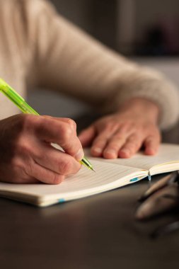 Kalem tutan insanın resmini kapat ve defterdeki boş beyaz sayfaya bir şeyler yaz