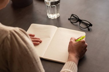 Düz not defterine kalem ile el yazısı notlarının yan görünümü. Doğal ışıklandırmalı minimalist çalışma alanı