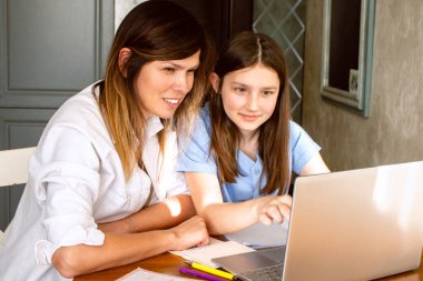 Kızı, internette dizüstü bilgisayarda heyecanlı bir şey gösteriyor. Mutfakta masada oturuyor. Ebeveynliğin ve anneliğin kutlu olsun. Mutlu aile kavramı