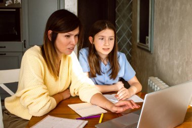 Aile dijital eğlence zamanı. Kafkas anne ve kızı dizüstü bilgisayar kullanarak online aktiviteler yapıyor, internette sörf yapıyor, iç mekanlarda video görüşmeleri yapıyor.