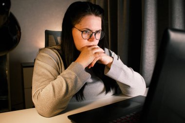 Odaklanmış iş kadını bilgisayarla sanal iş görüşmesi yapıyor. Evde oturan serbest çalışan, video konferansına katılıyor