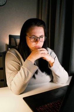 Odaklanmış iş kadını bilgisayarla sanal iş görüşmesi yapıyor. Evde oturan serbest çalışan, video konferansına katılıyor