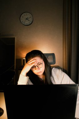 Baş ağrısı yüzünden bilgisayarda çalışan yorgun bir kadın kafasına dokunuyor. Migreni olan bir ofis çalışanı. İş yerinde acı çeken çok çalışan stresli bir çalışan.