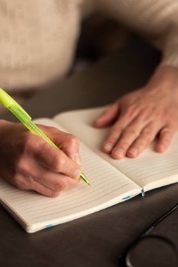 Düz not defterine kalem ile el yazısı notlarının yan görünümü. Doğal ışıklandırmalı minimalist çalışma alanı