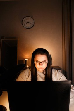 Gözlüklü genç bir kadın gece geç saatlerde evde bilgisayar başında çalışıyor, modern teknolojileri kullanıyor ve çevrimiçi eğitim alıyor. Uzaktan öğrenme konsepti. Online üniversite. Sürece odaklan