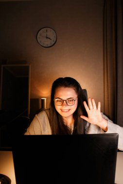 Gülümseyen kadın, video görüşmesi sırasında sevgili insanları diz üstü bilgisayarla selamlıyor. Uzakta yaşayan birine sevgi yollamak. Arkadaşlarla veya akrabalarla çevrimiçi konferans