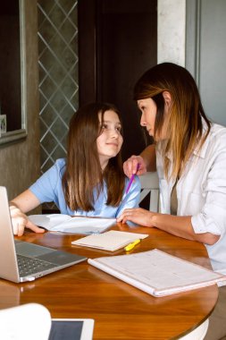 Aile dijital eğlence zamanı. Kafkas anne ve kızı dizüstü bilgisayar kullanarak online aktiviteler yapıyor, internette sörf yapıyor, iç mekanlarda video görüşmeleri yapıyor.