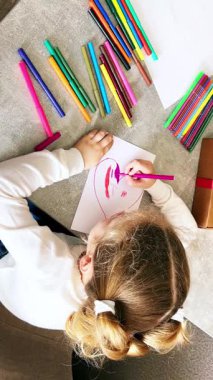 Küçük kız oturma odasındaki masada otururken çizim işlemine daldı. Çocuk eğitimi, ebeveynlik ve çocuk gelişimi kavramları için mükemmel