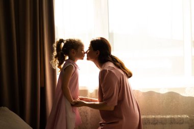 Anne ve kızının birbirlerine sevgi dolu fısıldaşmaları ve kıkırdamaları. Güvenli bağlılığın ve çocukluk mutluluğunun mükemmel bir örneği.