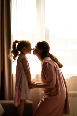 Kıkırdayan küçük kız ve annesi arasındaki burun okşama anı. Ebeveynlik, annelik ve aile ilişkileri konuları için ideal