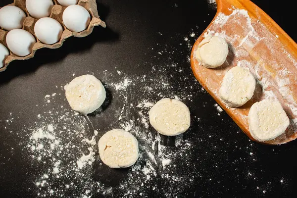 Syrniki yapma süreci. Kaymak hamurundan şerbet oluşturun. Siyah yüzeyin en üst görüntüsü. Rus mutfağı.