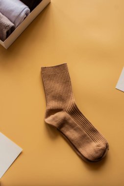 Açık sarı yüzeyde kahverengi bir çift çorap ve katlanmış çoraplar. Yumuşak ışıklandırmalı dikey Düz resim.
