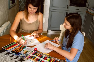 Anne, kızına evde oturarak resim çizmeyi öğretiyor. Aile sevgisinin samimi bir fotoğrafı. Eğitim, ebeveynlik ve yaşam tarzı içeriği için